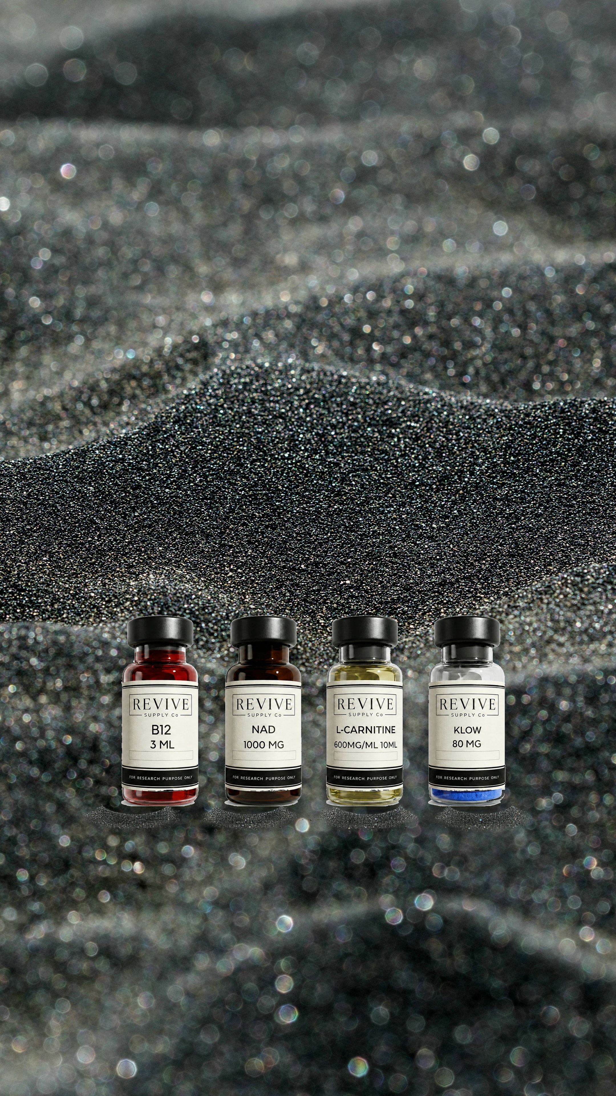 Revive Supply Co. B12, NAD, L-Carnitine, and KLOW vials resting on dark sand